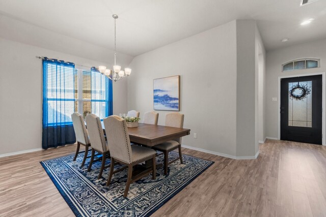 dining space with light hardwood / wood-style floors and a chandelier