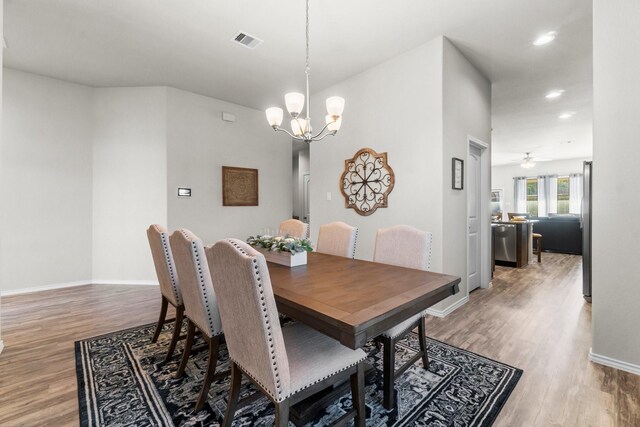 dining area featuring hardwood / wood-style floors and ceiling fan with notable chandelier