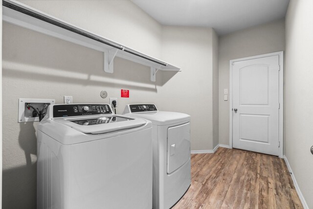 clothes washing area featuring washer and clothes dryer and wood-type flooring