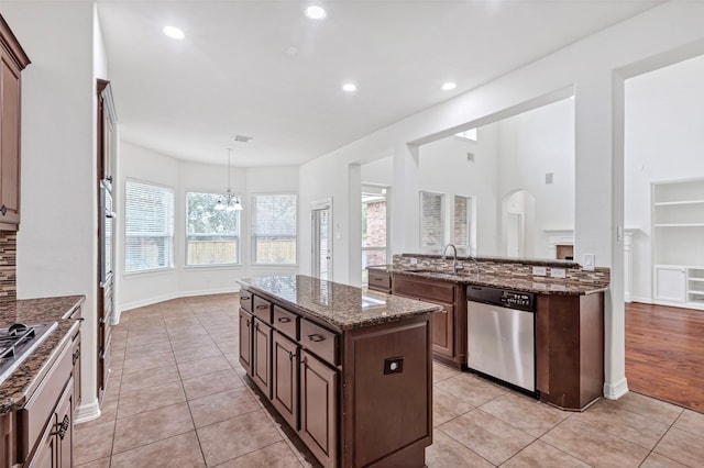 kitchen featuring light tile patterned flooring, pendant lighting, dark stone countertops, a center island, and stainless steel appliances