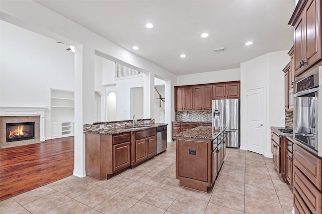 kitchen with backsplash, stainless steel appliances, a center island, and light tile patterned flooring