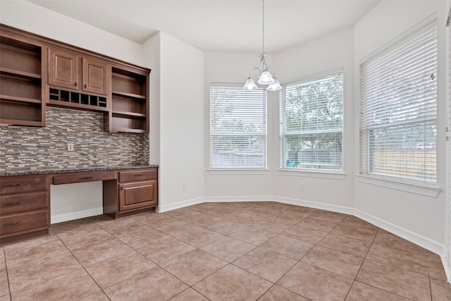 kitchen featuring pendant lighting, built in desk, decorative backsplash, and light tile patterned floors