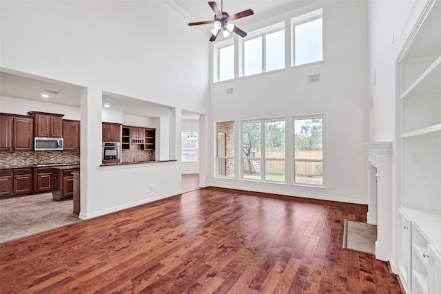 living room with ceiling fan, light hardwood / wood-style floors, and a high ceiling