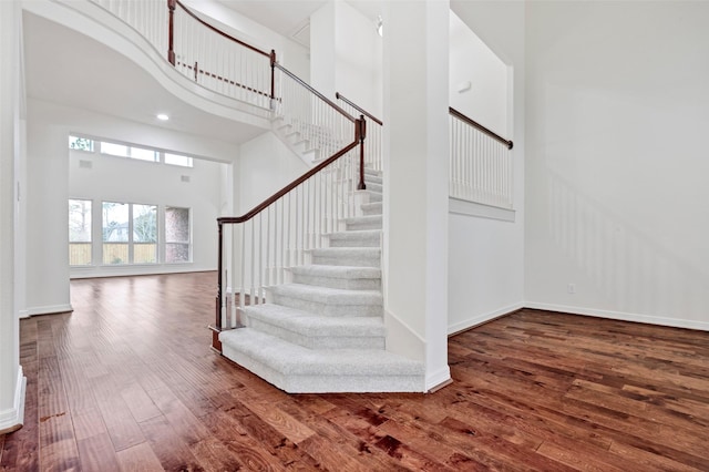 staircase featuring a high ceiling and hardwood / wood-style floors