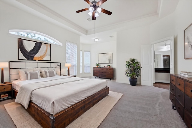 carpeted bedroom with a raised ceiling and ceiling fan