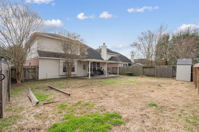 back of property with a patio area, a yard, and a storage shed