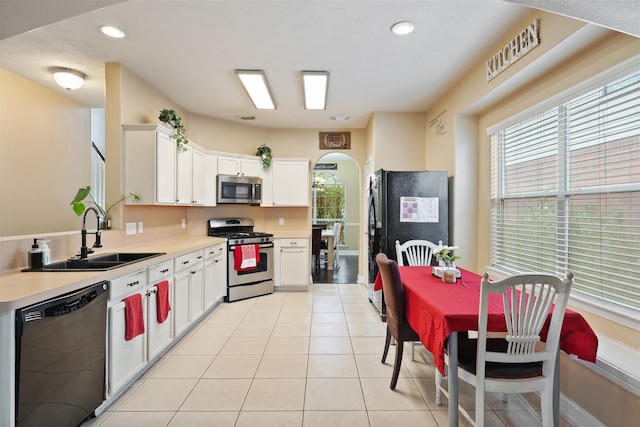 kitchen with light tile patterned floors, white cabinetry, sink, and black appliances