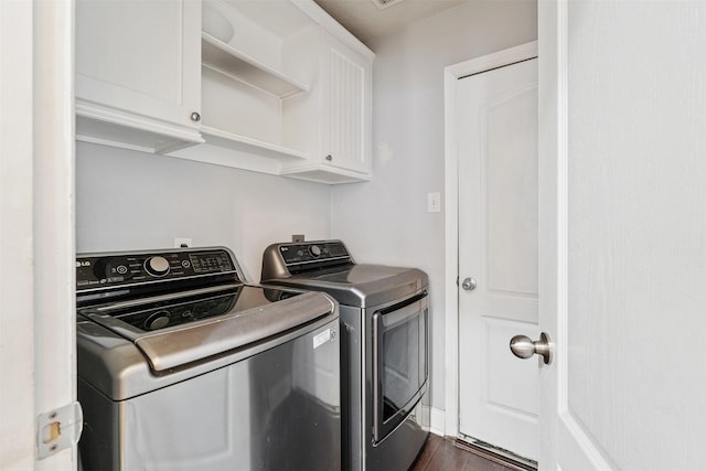 clothes washing area featuring dark wood-type flooring, cabinets, and separate washer and dryer