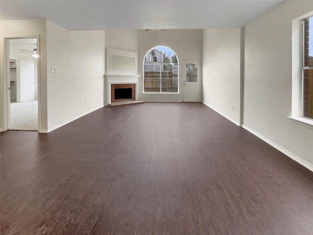 unfurnished living room with a brick fireplace and dark hardwood / wood-style floors