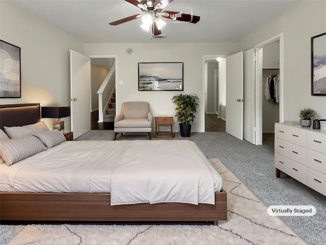 carpeted bedroom with a closet, ceiling fan, and a walk in closet