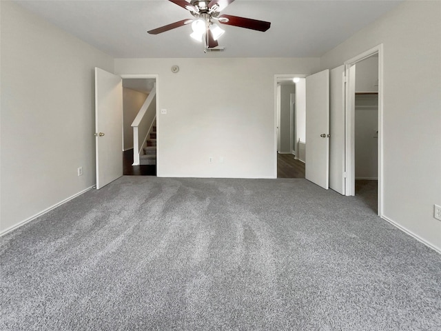 unfurnished bedroom featuring dark colored carpet, a spacious closet, and ceiling fan