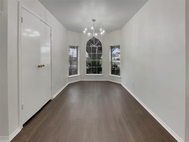 unfurnished dining area with an inviting chandelier and dark hardwood / wood-style floors