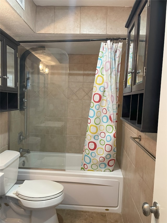 bathroom featuring tile walls, toilet, and shower / bath combination with curtain