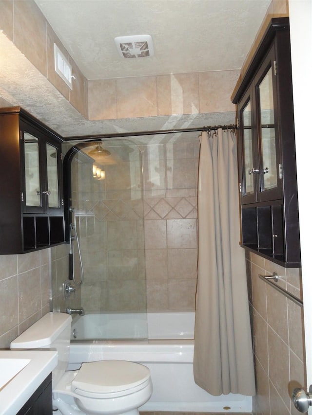 full bathroom featuring toilet, vanity, tile walls, and shower / bath combo with shower curtain