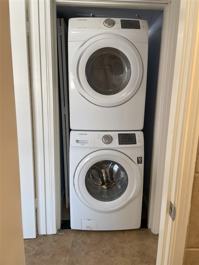 washroom with stacked washer / drying machine and tile patterned floors