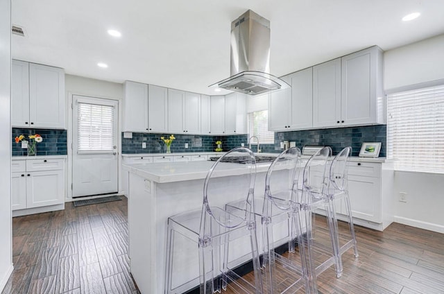 8614 Linkpass Ln, Houston, TX 77025 - kitchen featuring island range hood, a kitchen breakfast bar, plenty of natural light, tasteful backsplash, and recessed lighting
