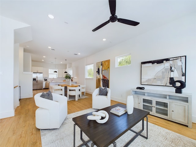 living room featuring ceiling fan, sink, and light hardwood / wood-style flooring