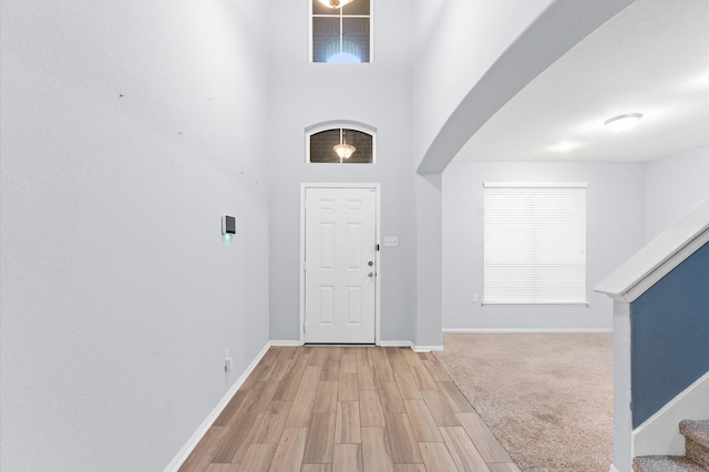 entryway featuring light wood-type flooring and a towering ceiling