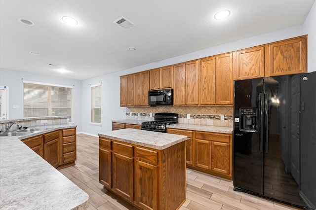 kitchen with black appliances, sink, tasteful backsplash, and a kitchen island