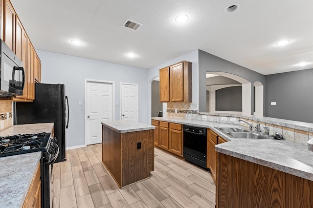 kitchen with black appliances, sink, tasteful backsplash, and a kitchen island