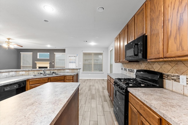 kitchen featuring black appliances, decorative backsplash, sink, light wood-type flooring, and ceiling fan