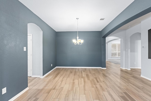 unfurnished room featuring a notable chandelier and light hardwood / wood-style flooring