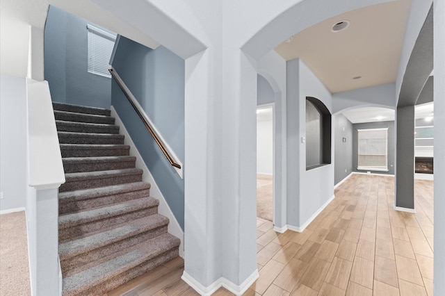 stairs with hardwood / wood-style flooring and a fireplace