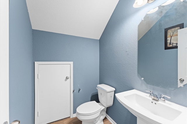 bathroom featuring toilet, vaulted ceiling, sink, and wood-type flooring