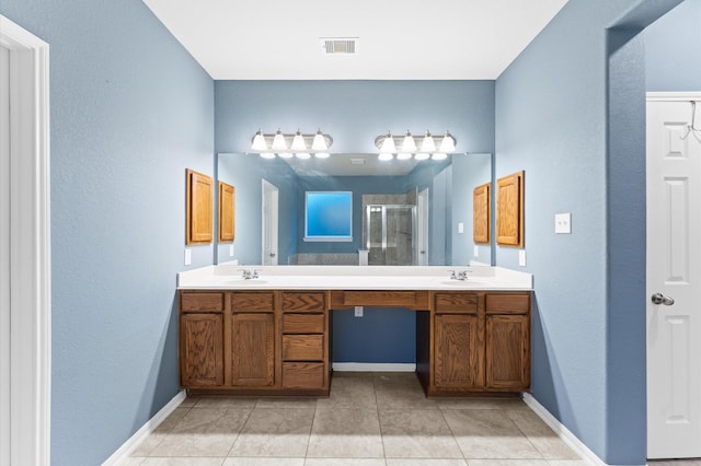 bathroom with a shower with shower door, vanity, and tile patterned flooring