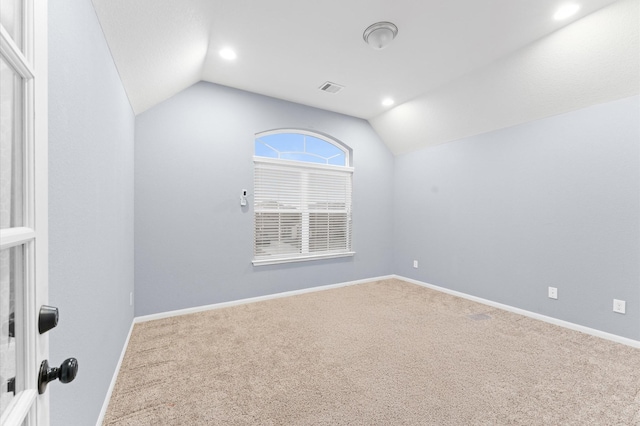 carpeted spare room with vaulted ceiling