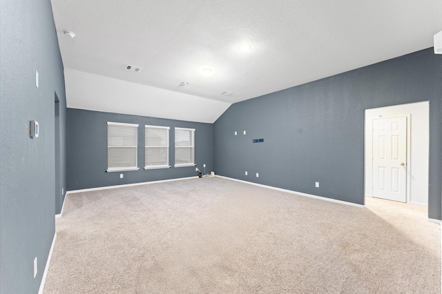 carpeted spare room featuring a textured ceiling and vaulted ceiling