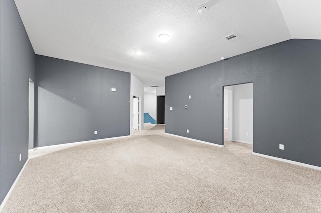 spare room featuring light carpet, a textured ceiling, and lofted ceiling