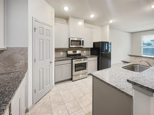 kitchen featuring stone countertops, sink, white cabinets, ornamental molding, and stainless steel appliances