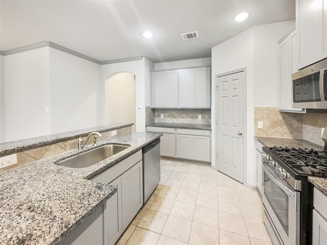 kitchen with light stone countertops, appliances with stainless steel finishes, tasteful backsplash, sink, and light tile patterned flooring