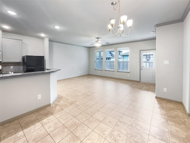 kitchen featuring dark stone countertops, a healthy amount of sunlight, ornamental molding, and black fridge