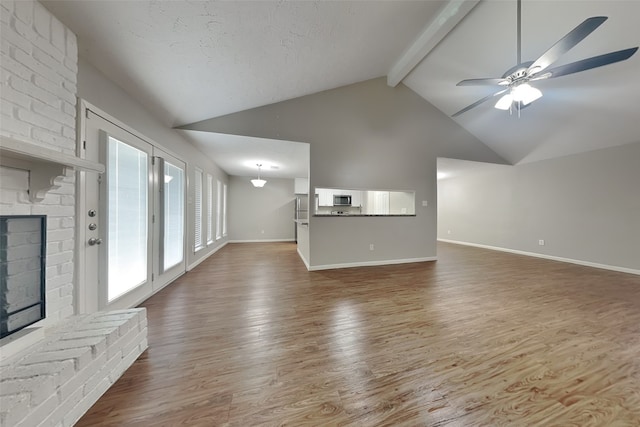 unfurnished living room featuring beamed ceiling, ceiling fan, hardwood / wood-style flooring, high vaulted ceiling, and a brick fireplace