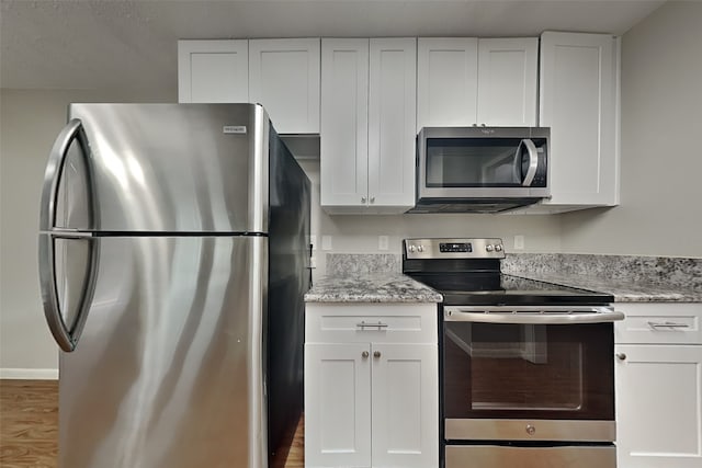 kitchen with light stone countertops, white cabinetry, and appliances with stainless steel finishes