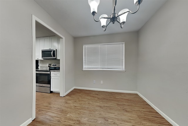 kitchen featuring white cabinets, an inviting chandelier, stainless steel appliances, and light hardwood / wood-style flooring