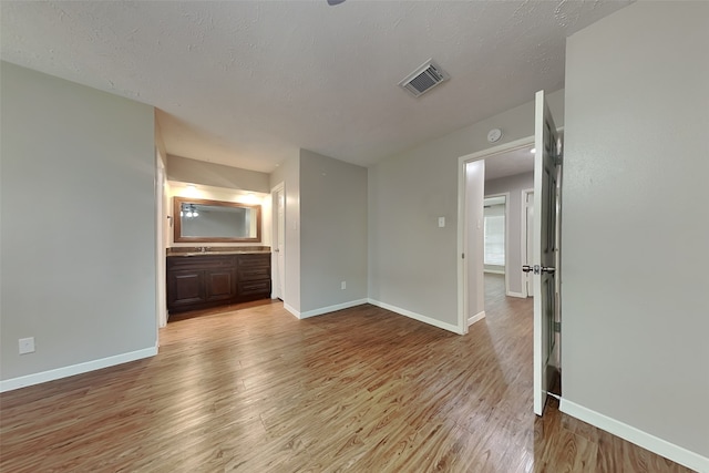 empty room with a textured ceiling and light hardwood / wood-style flooring