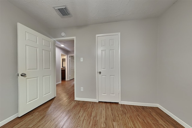 empty room featuring a textured ceiling and light hardwood / wood-style floors