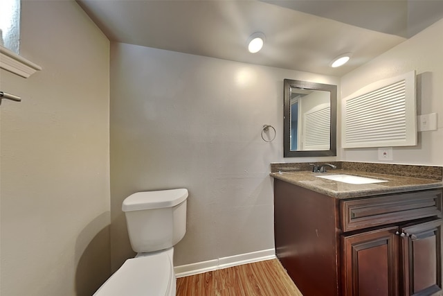 bathroom with toilet, hardwood / wood-style flooring, and vanity