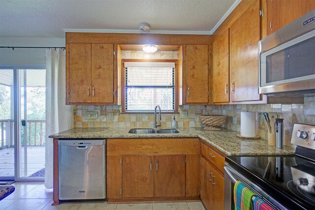 kitchen with appliances with stainless steel finishes, tasteful backsplash, light stone counters, and sink