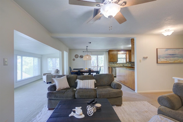 living room featuring ceiling fan, light colored carpet, and sink