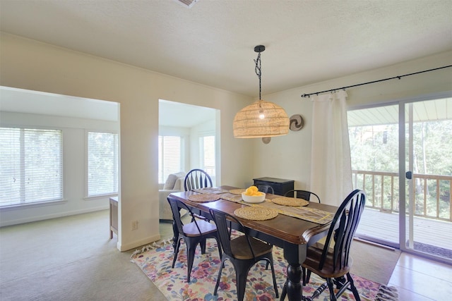 dining room featuring light colored carpet, plenty of natural light, and a textured ceiling