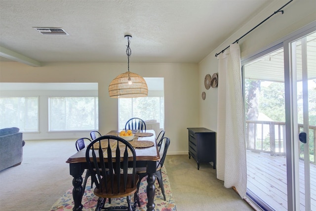 dining room with light colored carpet and a textured ceiling