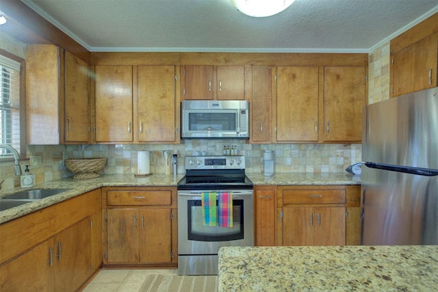 kitchen with appliances with stainless steel finishes, backsplash, light stone countertops, ornamental molding, and sink