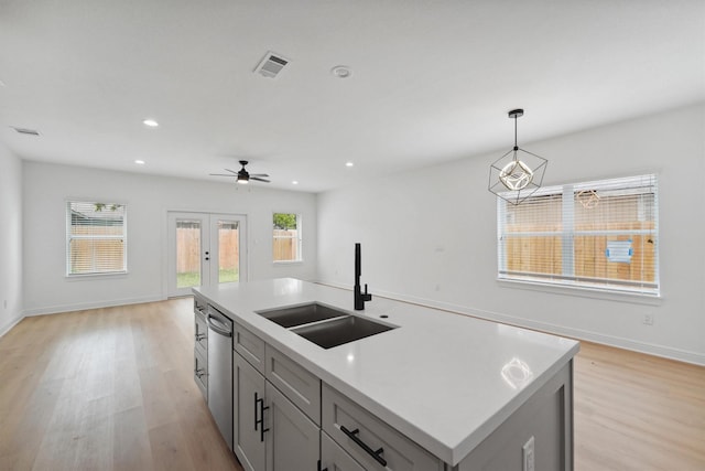 kitchen featuring dishwasher, gray cabinets, a center island with sink, sink, and french doors