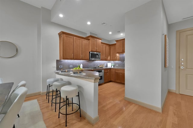 kitchen featuring stainless steel appliances, a kitchen breakfast bar, and light hardwood / wood-style floors