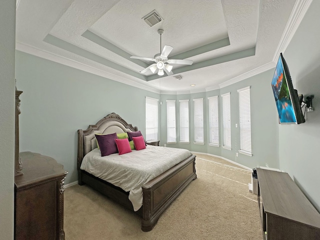 bedroom with crown molding, light colored carpet, a tray ceiling, and a textured ceiling