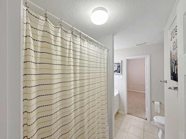 bathroom featuring toilet, a textured ceiling, vanity, curtained shower, and tile patterned flooring